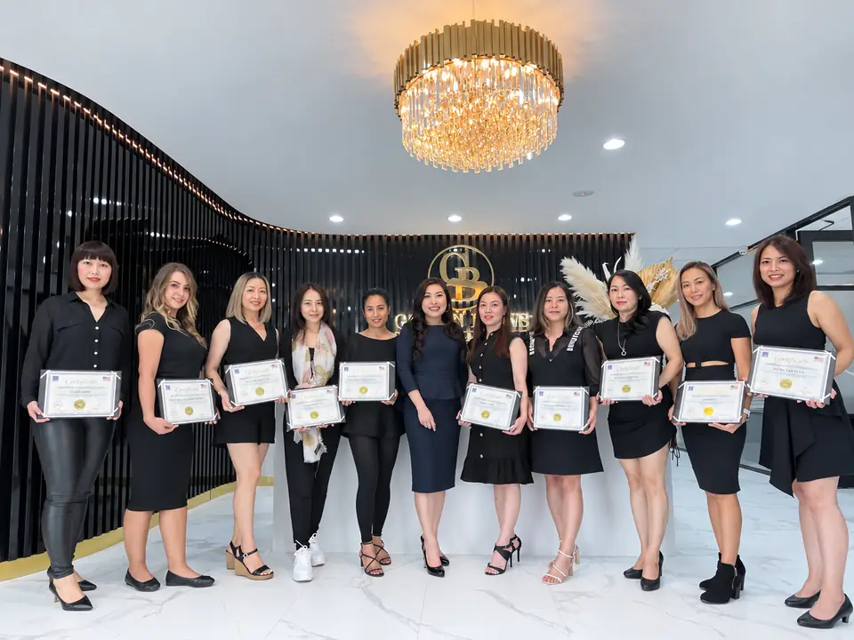 A graduating class at Golden Brows Academy, holding their certificates