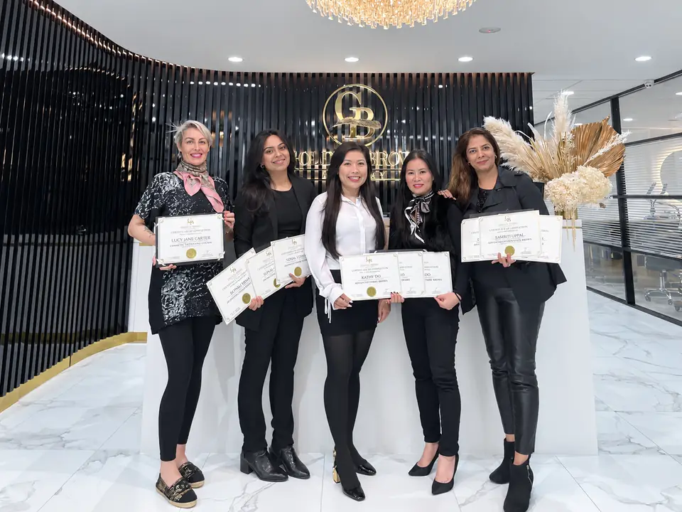 A graduating class at Golden Brows Academy, holding their certificates
