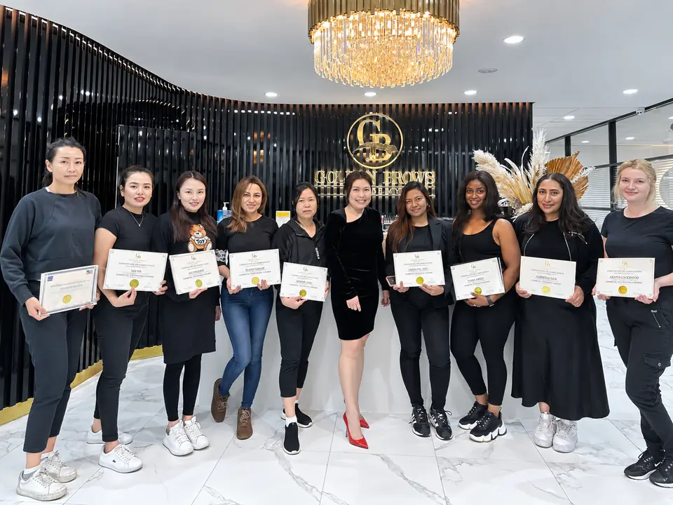A graduating class at Golden Brows Academy, holding their certificates