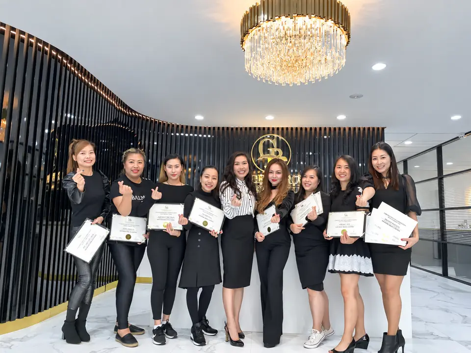 A graduating class at Golden Brows Academy, holding their certificates