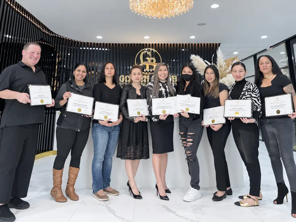 A graduating class at Golden Brows Academy, holding their certificates