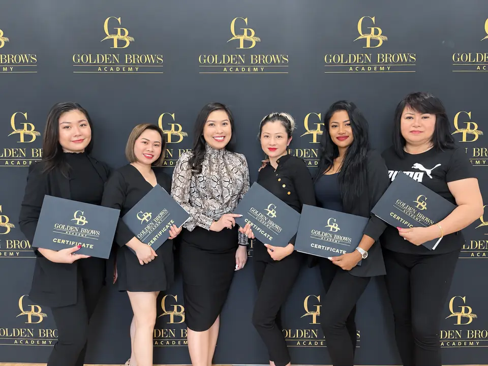 A graduating class at Golden Brows Academy, holding their certificates