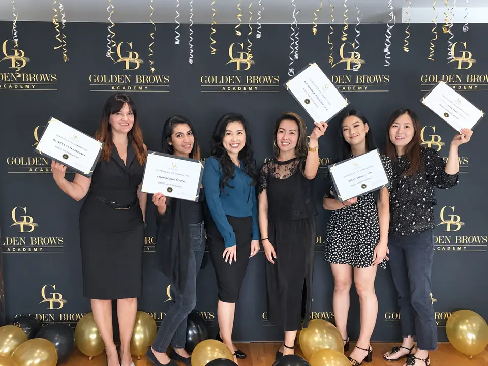 A graduating class at Golden Brows Academy, holding their certificates