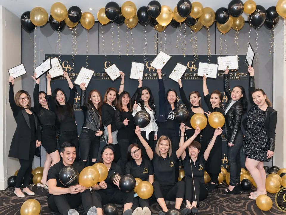 A graduating class at Golden Brows Academy, holding their certificates