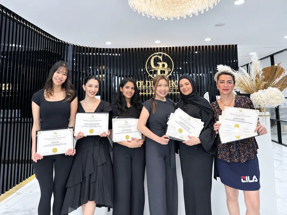 A graduating class at Golden Brows Academy, holding their certificates