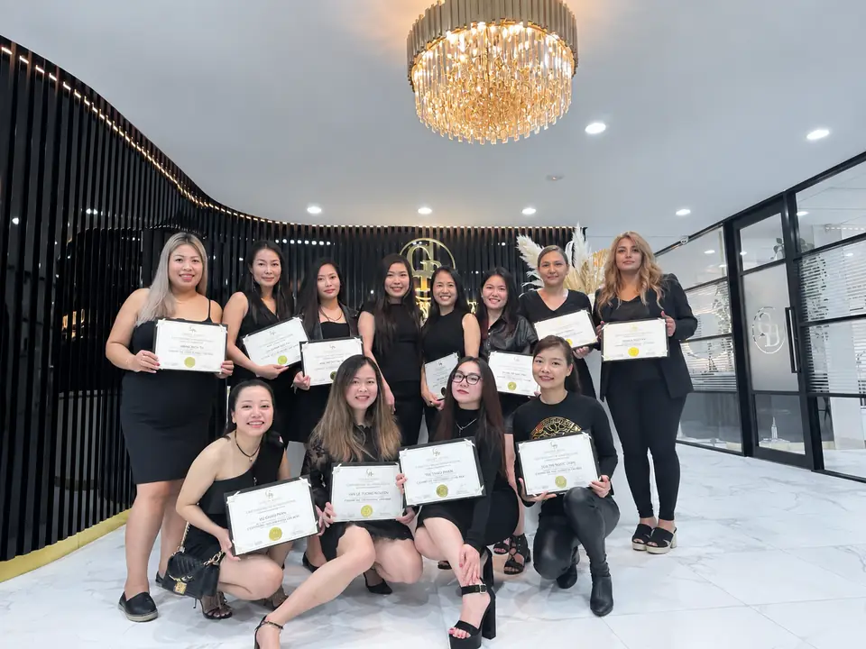 A graduating class at Golden Brows Academy, holding their certificates